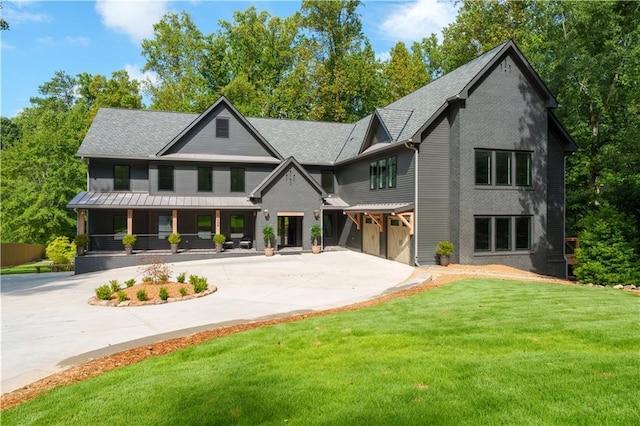 back of house with a garage, covered porch, and a lawn