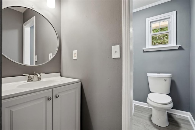 bathroom with vanity, toilet, ornamental molding, and hardwood / wood-style flooring