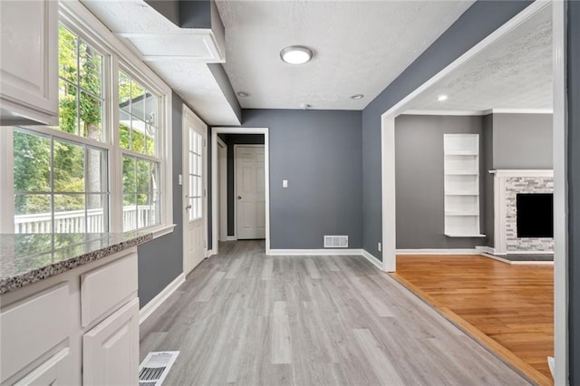 interior space with a fireplace, a textured ceiling, and light hardwood / wood-style floors