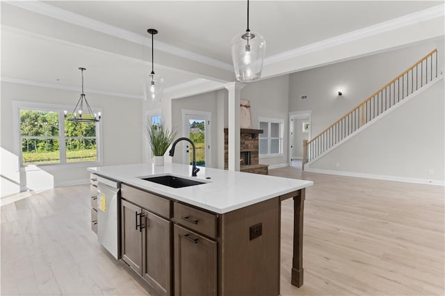 kitchen with white dishwasher, light stone counters, sink, and hanging light fixtures