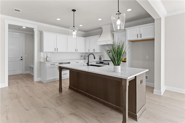 kitchen featuring white cabinets, sink, premium range hood, and a kitchen island with sink