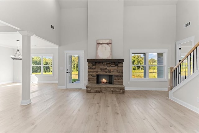 unfurnished living room featuring a towering ceiling, light hardwood / wood-style flooring, and a wealth of natural light