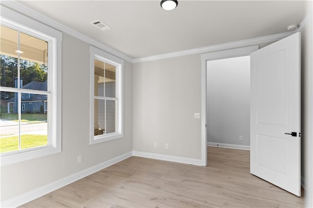 spare room with a healthy amount of sunlight, light wood-type flooring, and crown molding