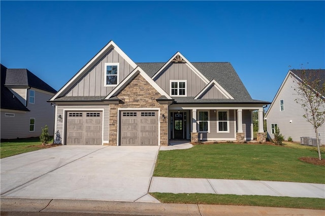 craftsman house with central air condition unit, a front lawn, a porch, and a garage