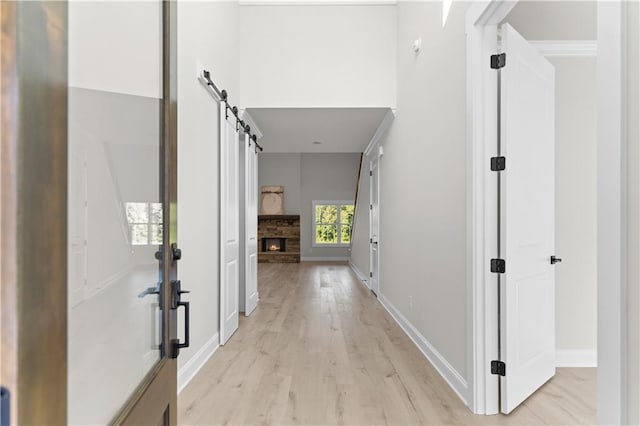 corridor with a barn door and light hardwood / wood-style flooring