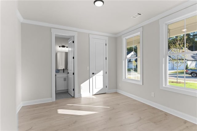 spare room featuring light wood-type flooring, a wealth of natural light, and crown molding