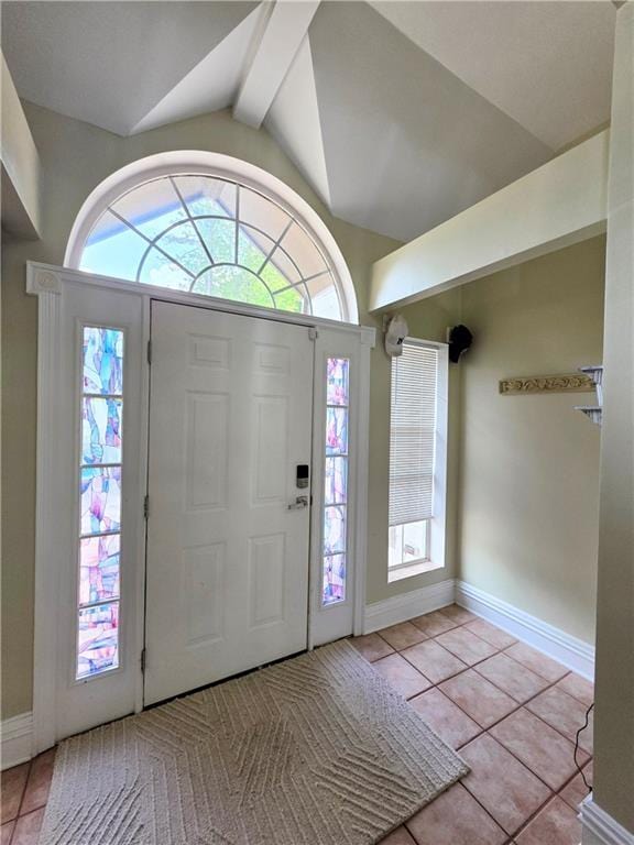 tiled foyer entrance featuring lofted ceiling with beams, baseboards, and a healthy amount of sunlight