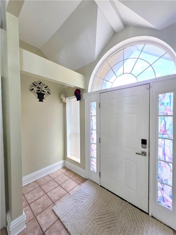 tiled foyer entrance featuring baseboards and lofted ceiling