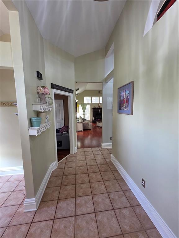 hall with a high ceiling, tile patterned floors, and baseboards