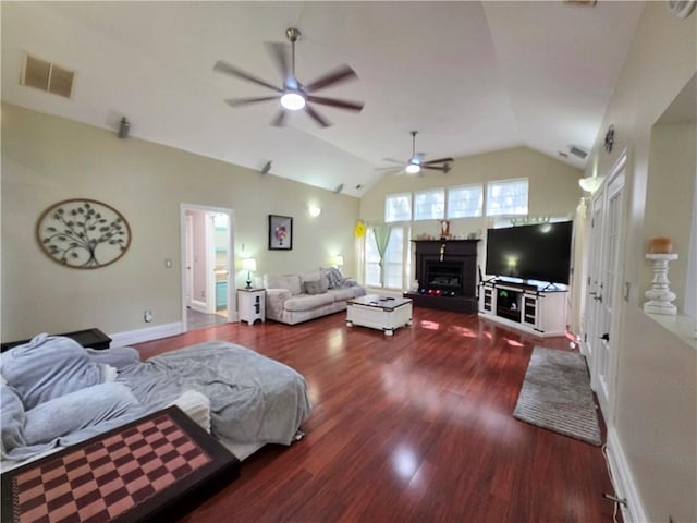 living room with wood finished floors, visible vents, a ceiling fan, a lit fireplace, and lofted ceiling