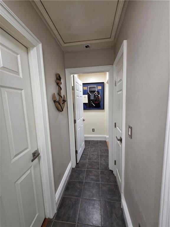 hall with attic access, dark tile patterned flooring, and baseboards