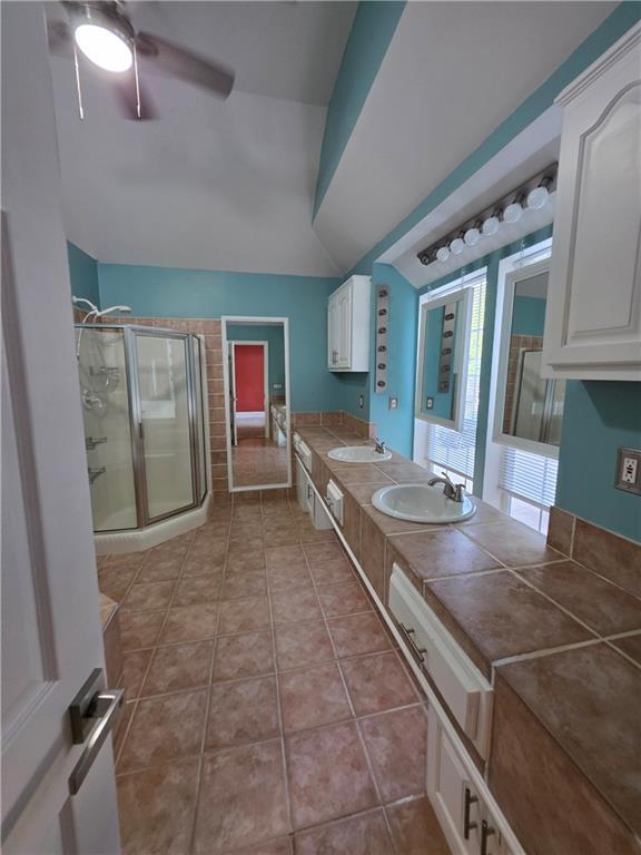 200 Valley Brook Dr, Newnan, GA 30265 - bathroom with a stall shower, ceiling fan, double vanity, vaulted ceiling, and tile patterned flooring