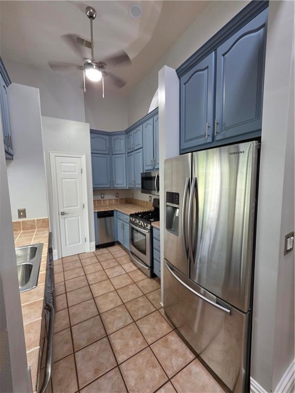 200 Valley Brook Dr, Newnan, GA 30265 - kitchen featuring stainless steel appliances, blue cabinetry, ceiling fan, light countertops, and a sink