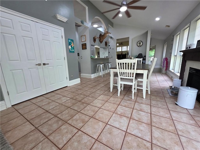 dining space featuring lofted ceiling, light tile patterned floors, ceiling fan, baseboards, and a fireplace