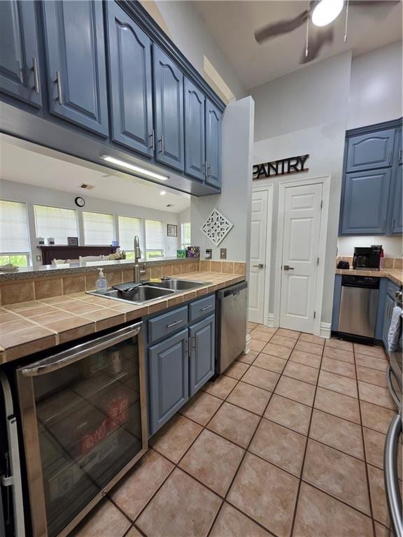 kitchen featuring tile counters, blue cabinetry, and stainless steel dishwasher