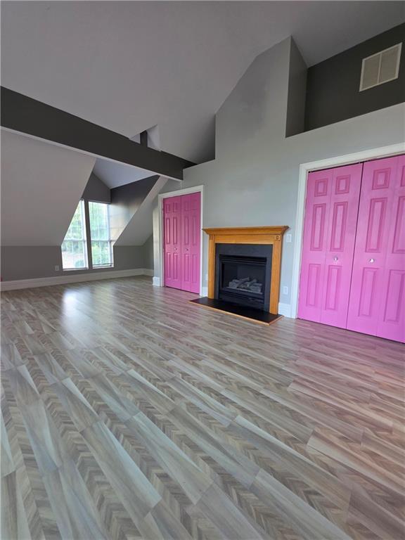 200 Valley Brook Dr, Newnan, GA 30265 - unfurnished living room featuring wood finished floors, a fireplace with raised hearth, baseboards, and high vaulted ceiling