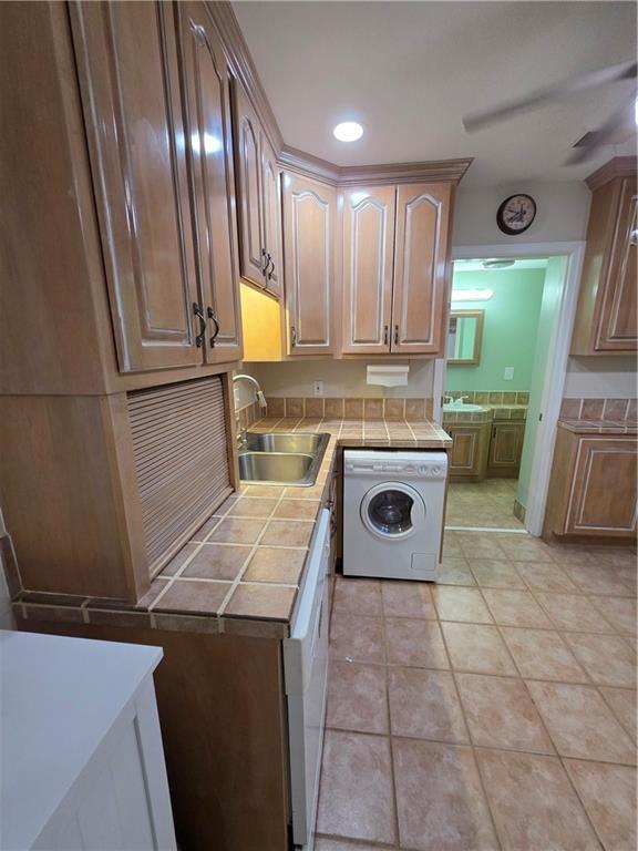 washroom with light tile patterned floors, washer / dryer, laundry area, and a sink