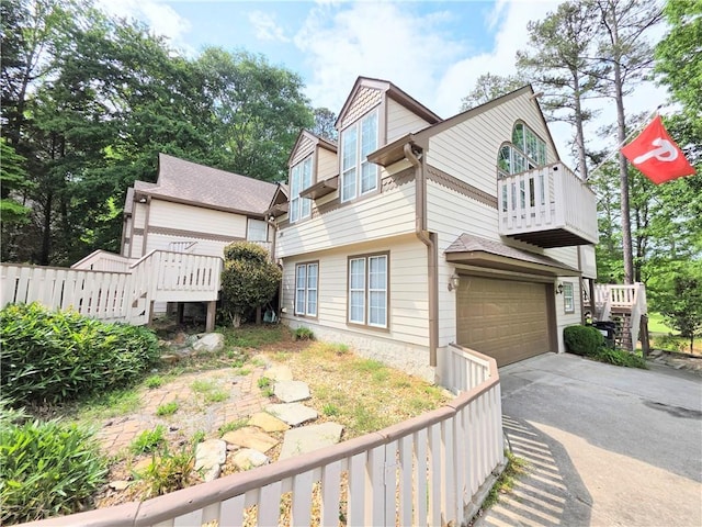 view of property exterior featuring stairway, fence, driveway, a balcony, and an attached garage