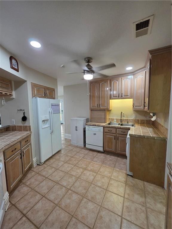 kitchen featuring a sink, ceiling fan, visible vents, tile countertops, and white appliances