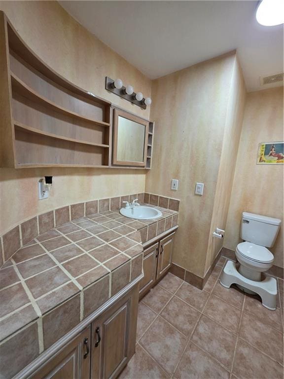 bathroom with tile patterned floors, toilet, vanity, baseboards, and visible vents