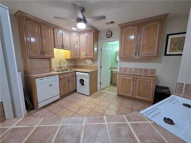 kitchen with a sink, white dishwasher, washer / dryer, a ceiling fan, and tile countertops