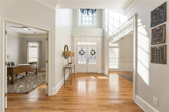 foyer featuring crown molding, light hardwood / wood-style flooring, and a high ceiling