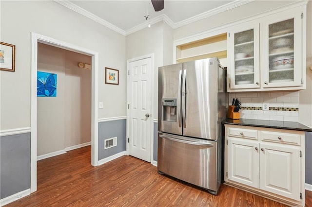 kitchen featuring white cabinets, wood-type flooring, backsplash, stainless steel fridge, and crown molding