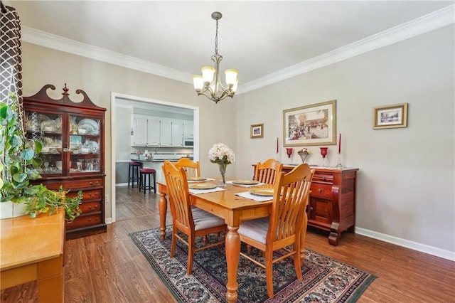 dining area with ornamental molding, an inviting chandelier, and dark hardwood / wood-style flooring