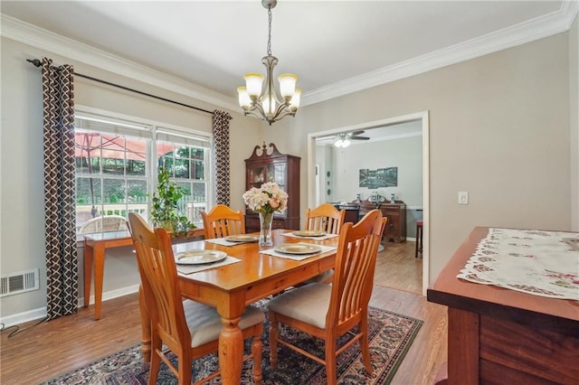 dining area with ceiling fan with notable chandelier, ornamental molding, and light wood-type flooring