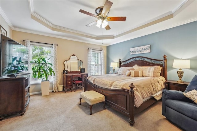 carpeted bedroom with ceiling fan, a raised ceiling, and ornamental molding