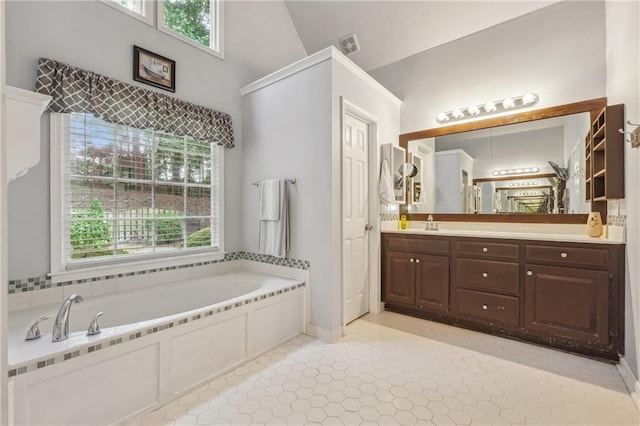 bathroom featuring a tub to relax in, tile patterned floors, lofted ceiling, and vanity