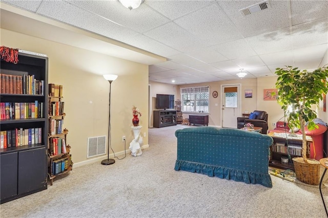 living room with a paneled ceiling and carpet floors