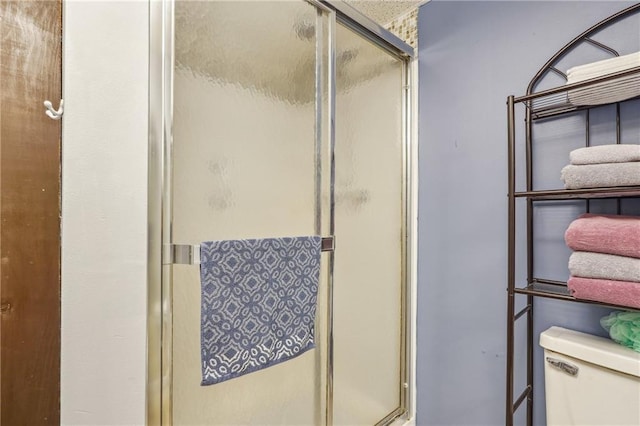 bathroom with a shower with door and toilet