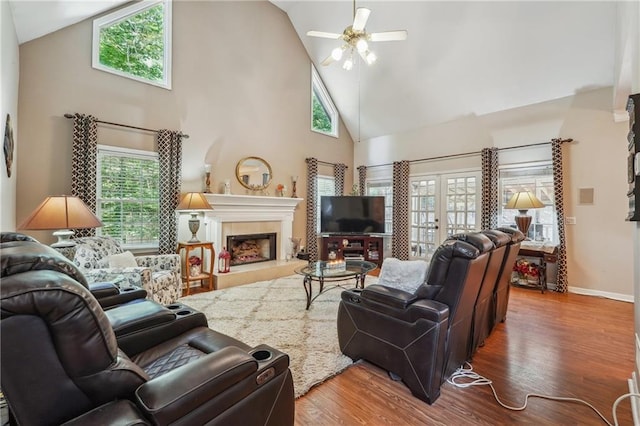 living room featuring wood-type flooring, a fireplace, high vaulted ceiling, and ceiling fan