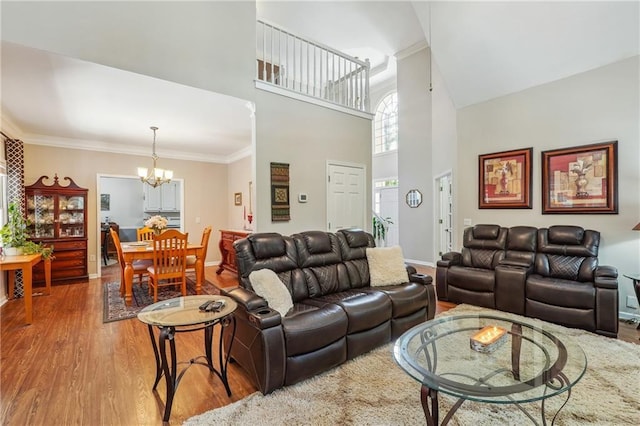 living room featuring hardwood / wood-style flooring, a chandelier, ornamental molding, and a towering ceiling