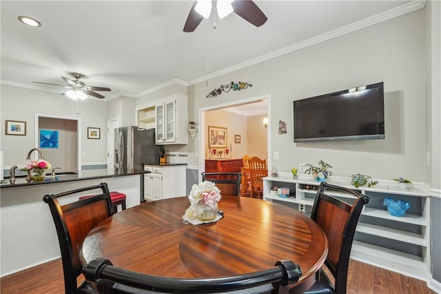 dining space with sink, ceiling fan, crown molding, and dark hardwood / wood-style floors