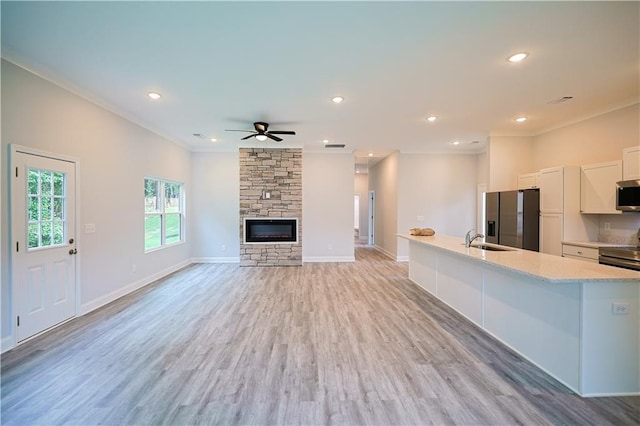 275 Green Commons Dr, Covington, GA 30016 - kitchen featuring appliances with stainless steel finishes, white cabinets, a sink, a fireplace, and crown molding