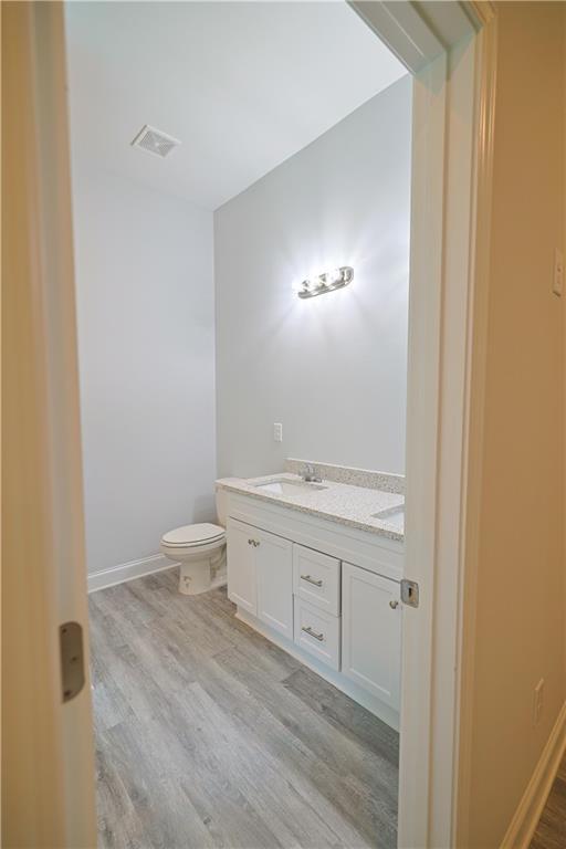 275 Green Commons Dr, Covington, GA 30016 - bathroom with double vanity, toilet, wood finished floors, and baseboards