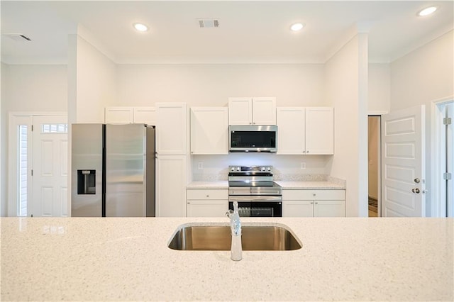 275 Green Commons Dr, Covington, GA 30016 - kitchen featuring appliances with stainless steel finishes, a sink, light stone counters, white cabinetry, and recessed lighting