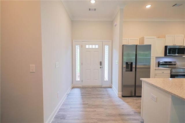 275 Green Commons Dr, Covington, GA 30016 - kitchen with appliances with stainless steel finishes, light wood-style flooring, crown molding, white cabinets, and baseboards