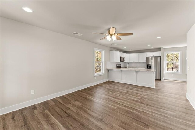 kitchen with kitchen peninsula, plenty of natural light, white cabinets, and appliances with stainless steel finishes