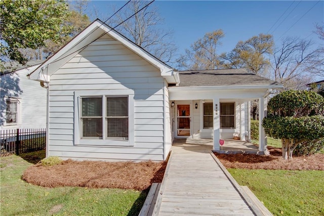 bungalow-style house featuring a shingled roof, fence, and a porch
