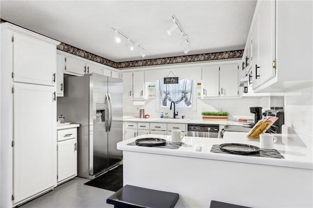 kitchen featuring white cabinetry, appliances with stainless steel finishes, kitchen peninsula, and sink