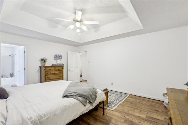 bedroom featuring hardwood / wood-style flooring, ceiling fan, a raised ceiling, and a textured ceiling