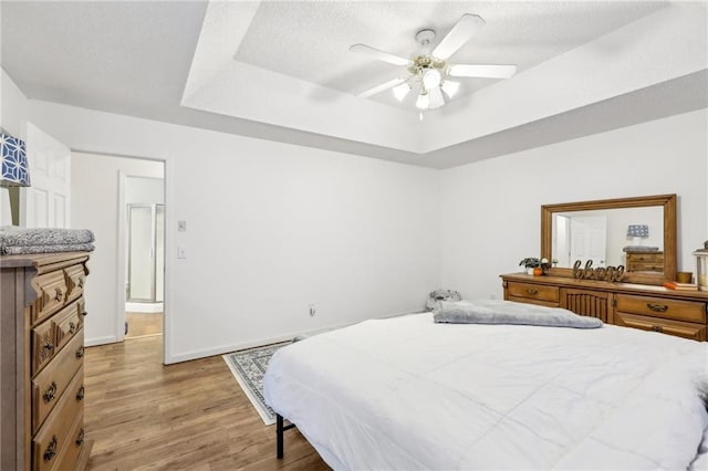 bedroom featuring a raised ceiling, ceiling fan, and light hardwood / wood-style floors