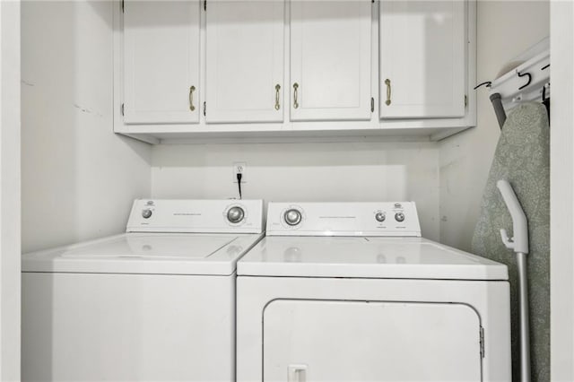 clothes washing area with cabinets and washing machine and dryer