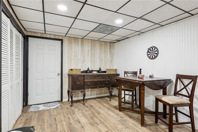 bar with a drop ceiling, dark brown cabinets, and light hardwood / wood-style flooring