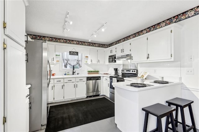 kitchen featuring appliances with stainless steel finishes, white cabinets, a kitchen bar, and kitchen peninsula