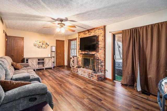 living room with a fireplace, a textured ceiling, wood finished floors, and a ceiling fan