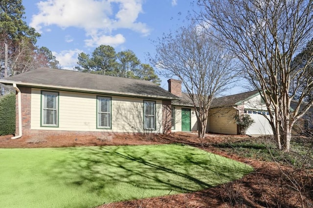 view of front of property with a front lawn, a chimney, an attached garage, and brick siding